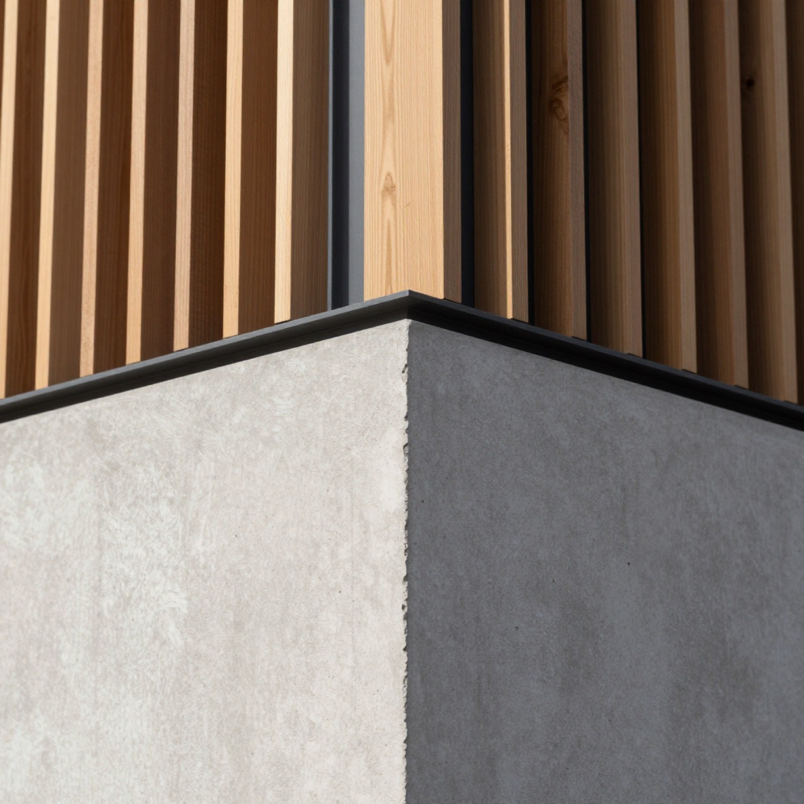 Detalle constructivo: esquina de hormigón, marco negro y listones
