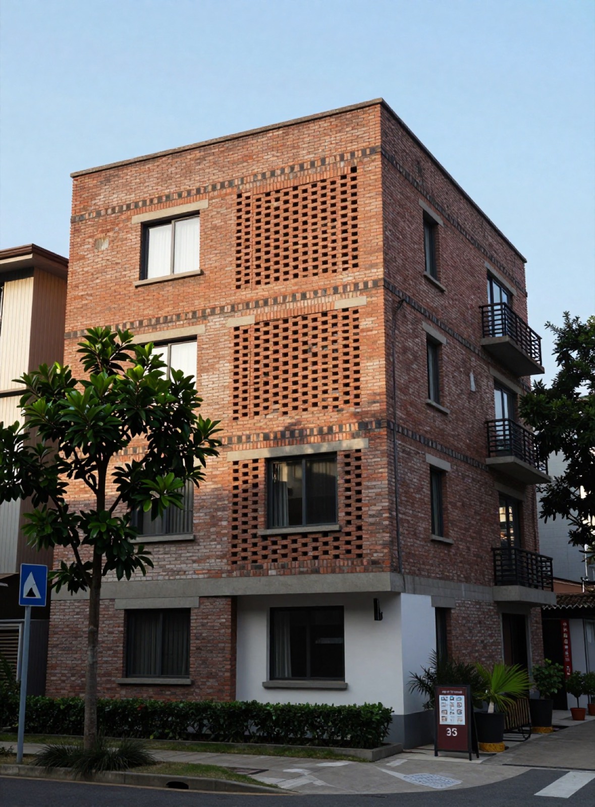 Edificio residencial de cinco pisos con fachada de ladrillo y celosías de ladrillo, árboles en la vereda