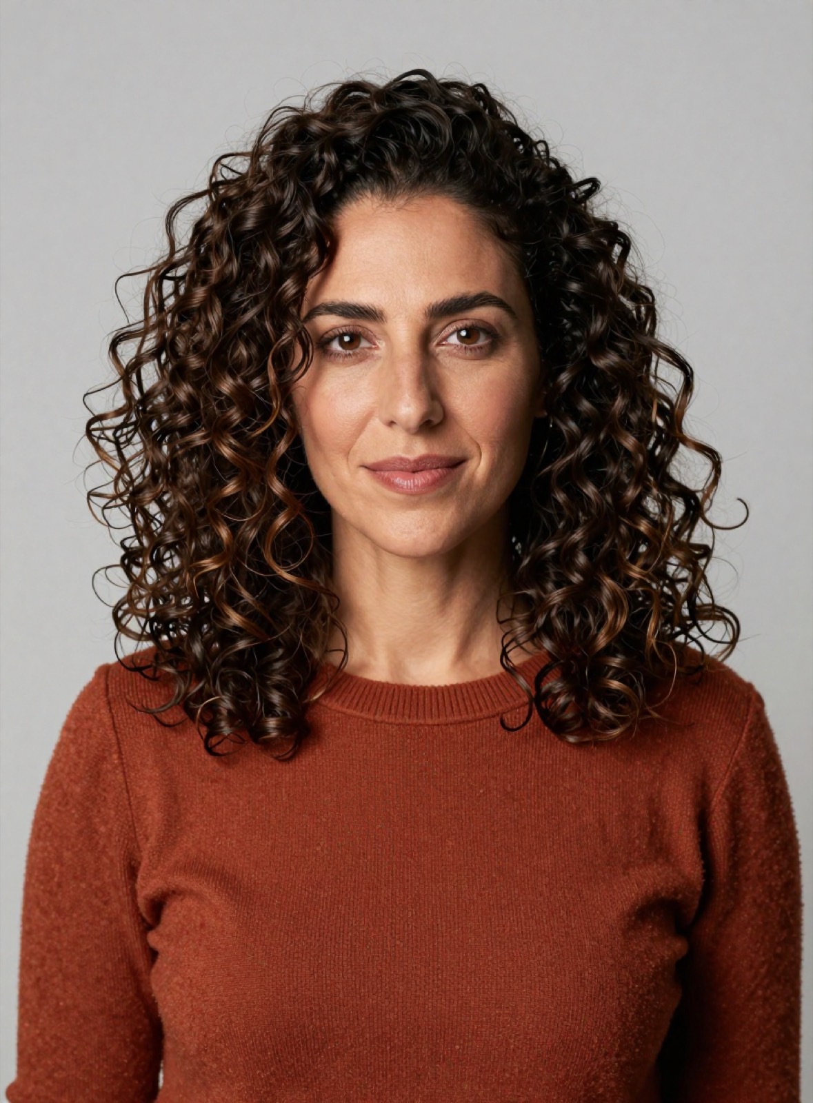 Retrato de Daniela Quispe: mujer de pelo castaño crespo, suéter color óxido